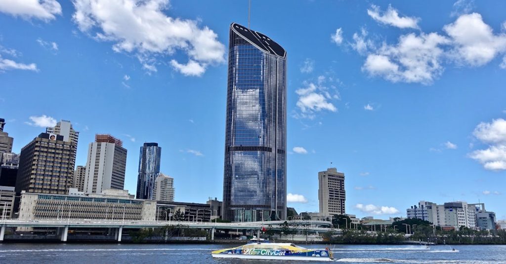 Ironbark software - Skyscraper in Brisbane skyline reflecting in river under blue sky with clouds.