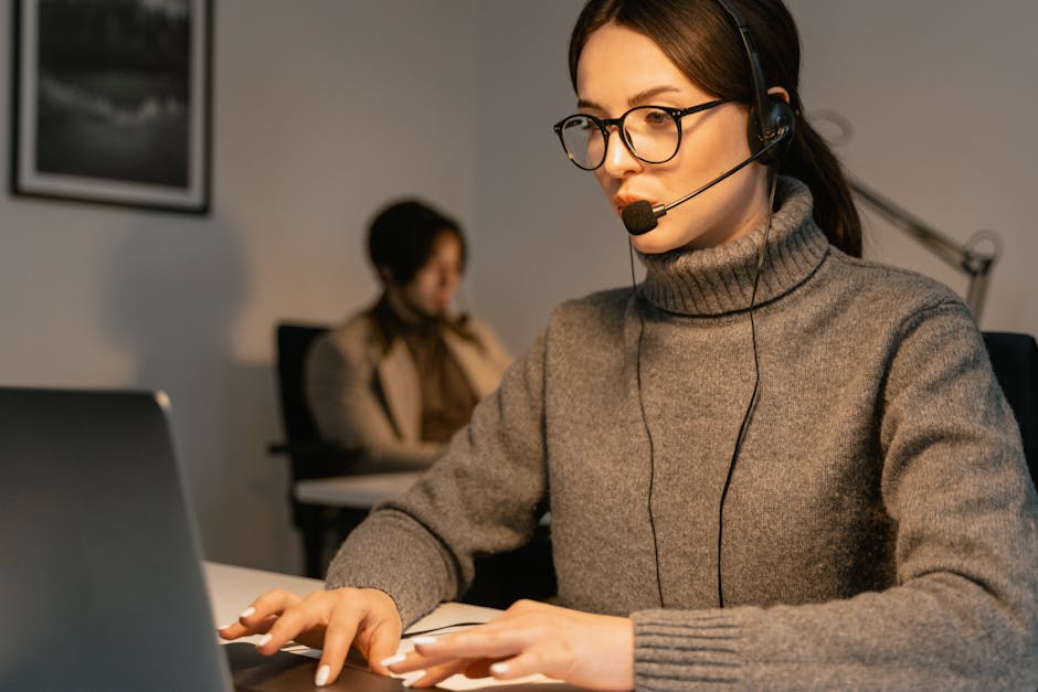 Image shows a professional woman wearing headset working in customer support role Image shows a professional woman wearing headset working in customer support role