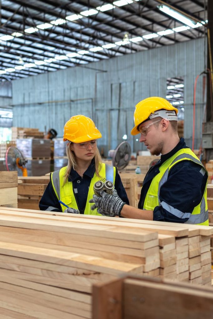 Image shows workers inspecting wood quality in a lumber warehouse